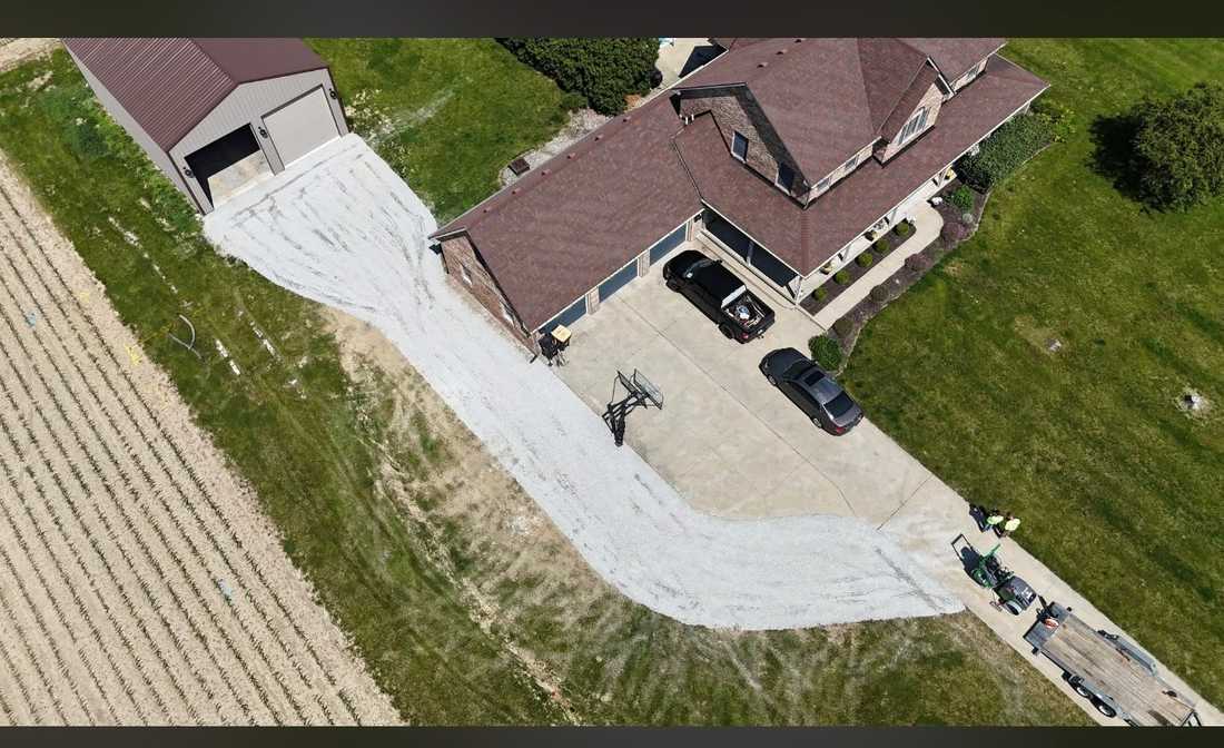 Aerial view of a new stone driveway running from a pole barn past a house